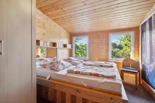 a bed in a wooden room with two windows at Ferienhaus 249 - Haus Seeblick in Zadelsdorf