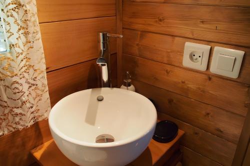 a white toilet in a bathroom with wooden walls at Roulotte De Cabrières in Compeyre