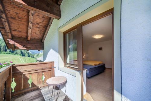 a room with a balcony with a bed and a window at Rieglhof Apartment Hennennest in Curon Venosta