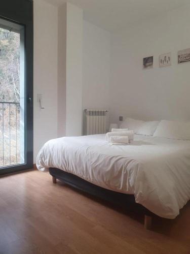 a bedroom with a bed with white sheets and a window at Altissim Font de Ferro in Ransol