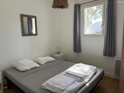 two beds in a bedroom with a window at Cottages des Pins in Saint-Hilaire-de-Riez