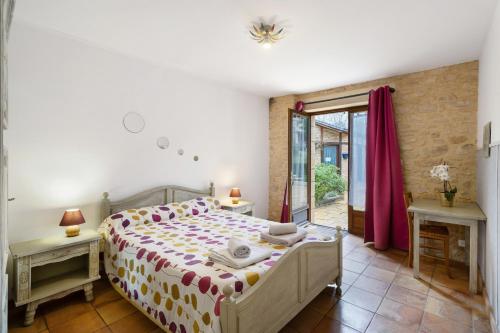 a bedroom with a bed and two tables and a window at La Ferme de la Croix d'Allon in Sarlat-la-Canéda