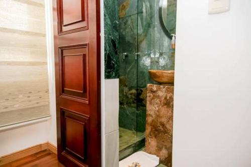 a bathroom with a shower and a wooden door at Casa Lavim in Bogotá