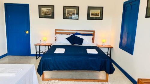 a bedroom with a blue and white bed with two tables at Casa da Dóta no paraíso de Furnas e Capitólio in São José da Barra