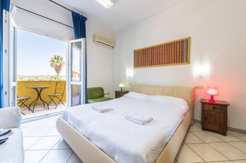 a bedroom with a bed and a balcony with a table at Domus Luna in Giba