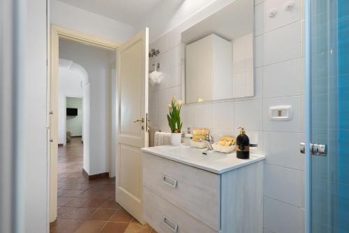 a white bathroom with a sink and a mirror at La Perla House in Anacapri