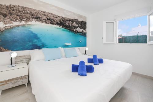 a white bedroom with a large bed with blue pillows at Villa Aday and Ixeia in Cala Blanca
