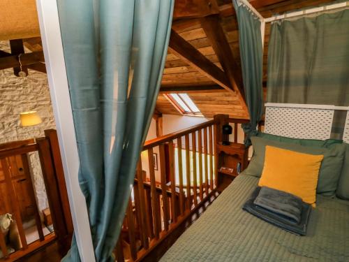 a balcony with a bed and a blue curtain at Swallows Nest in Newton Abbot