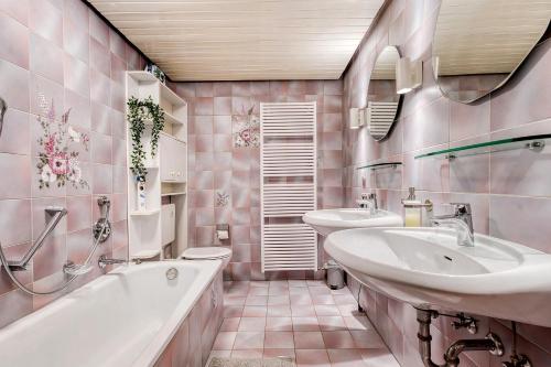 a pink bathroom with two sinks and a tub and a toilet at Am Linnert in Haltern