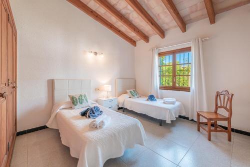 a room with two beds and a chair and a window at Finca Boy in Pollença