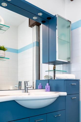 a blue bathroom with a sink and a mirror at Luna - Apartment by the beach in Lesa
