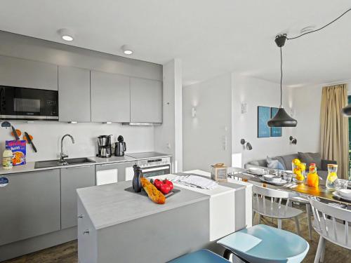a kitchen with white cabinets and a table with fruit on it at Apartment Seeflair by Interhome in Lembruch