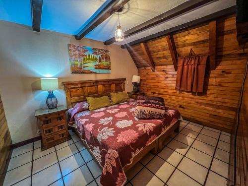 ein Schlafzimmer mit einem Bett und einer Holzwand in der Unterkunft Cabañas Lupita 22 in Mazamitla