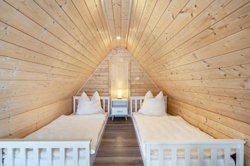 two beds in a room with a wooden ceiling at Auszeit Nr 18 in Zempin