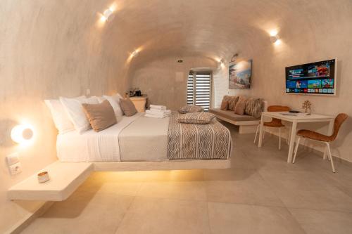 a bedroom with a large bed and a living room at Rody Caves Oia in Oia