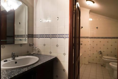 a bathroom with a sink and a toilet and a mirror at Casa do Mogadouro in Mesquitela