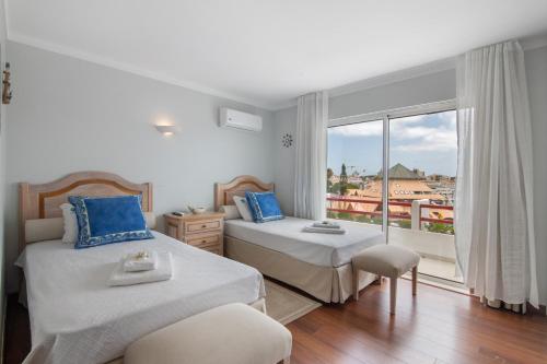 a bedroom with two beds and a large window at Marina Vilamoura Penthouse Luxury in Vilamoura