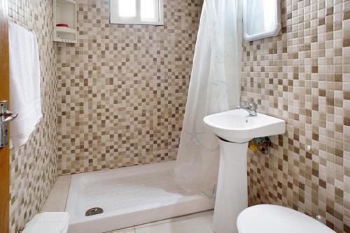 a bathroom with a sink and a shower and a toilet at El Faro Sardina in Sardina