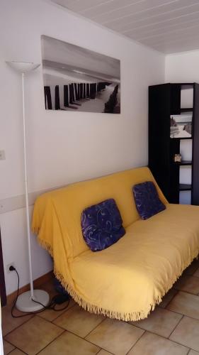 a yellow bed with two pillows on it in a room at T3 Mimizan Plage in Mimizan-Plage