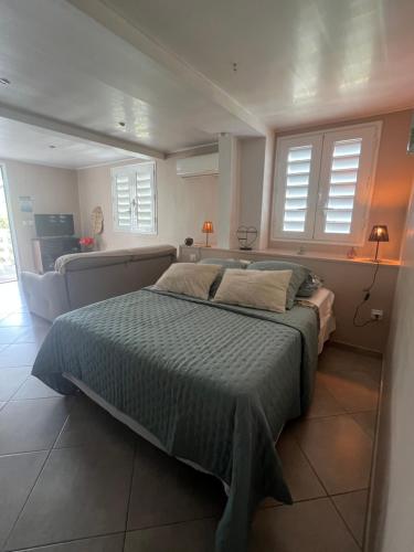 a bedroom with a bed and a couch and windows at Grand studio Plaisance et Fleurs in Le Vauclin