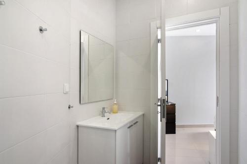 a white bathroom with a sink and a mirror at Skipper House in Loulé