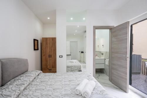 a white bedroom with a large bed and a bathroom at P&P Apartment in Forio d'Ischia