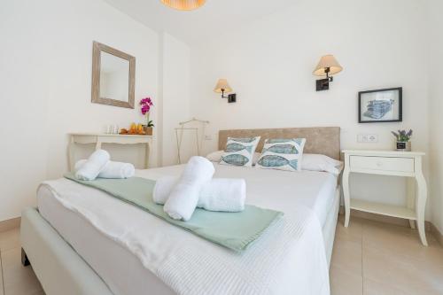 a white bedroom with two beds and a mirror at Apartamento Sf1 in L'Ametlla de Mar