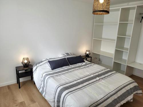 a bedroom with a bed with two night stands and shelves at Gîte Les Pirouettes in Pirou