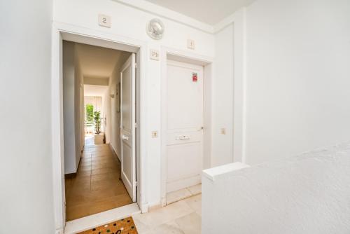 a hallway with white walls and a white door at Villa Orchidée - Coves Noves in Punta Grossa
