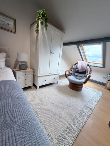 a bedroom with a bed and a chair and a cabinet at Stylish Maisonette with View in Tweedmouth