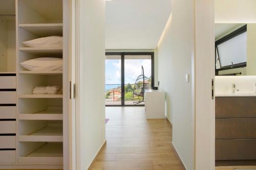 a room with white walls and a hallway with shelves at Casa Jolie in Ponta do Sol