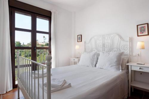 a white bed in a white bedroom with a window at Cobijadas75 Janda in Vejer de la Frontera