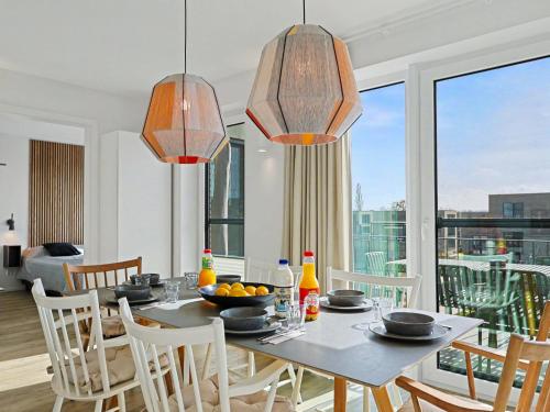 a dining room with a table and chairs and windows at Apartment Penthouse Dümmerblick - 619 by Interhome in Lembruch