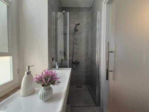 a bathroom with a shower and a vase of flowers on a sink at Kavcıoğlu Rooms in Urla