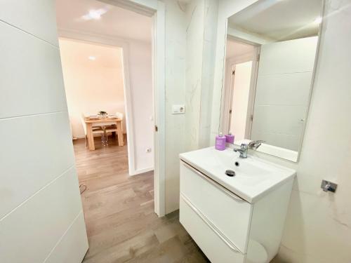 a white bathroom with a sink and a mirror at Atico Solarium La Cala in Miami Platja