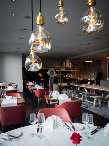 a restaurant with white tables and red chairs and chandeliers at Radisson Blu Hotel, St. Gallen in St. Gallen