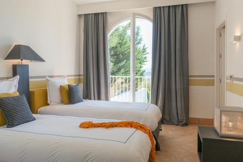 two beds in a hotel room with a window at Villa Muscari in Benalup Casas Viejas