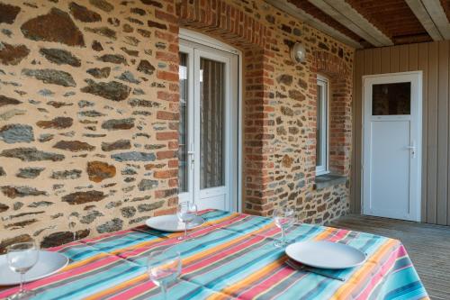 a table with plates and wine glasses on a stone wall at Grain de vanille in Saint-Benoît-des-Ondes