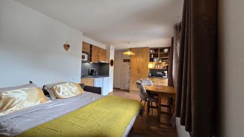 a bedroom with a bed and a table and a kitchen at Studio Edelweiss proche Megeve in Flumet