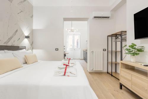 a white bedroom with a large white bed and a tv at Piccolo Incanto Spa Palermo in Palermo