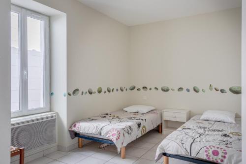 two beds in a white room with a window at Maison proche océan - 6 pers in Bretignolles-sur-Mer
