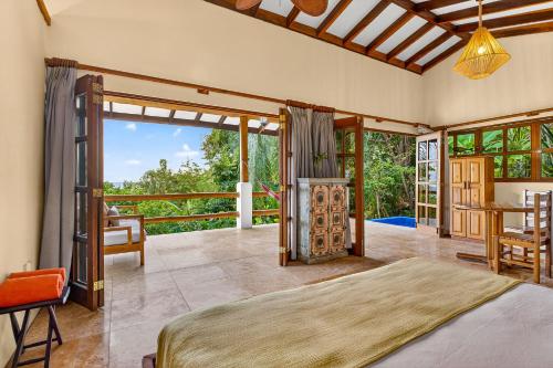 a bedroom with a bed and a table and a balcony at Ocio Villas Mal Pais in Santa Teresa Beach