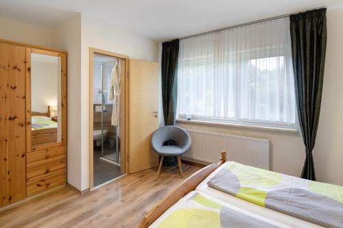 a bedroom with a bed and a window and a chair at Ferienwohnung Wiesenschneiders in Freiensteinau