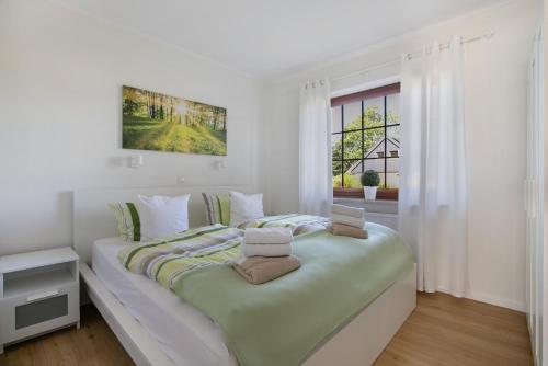 a white bedroom with a large bed with two laptops on it at Haus am Hemm in Meldorf