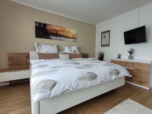 a bedroom with a large white bed and a television at Ferienwohnung Friedhoff, 80qm in Schmallenberg