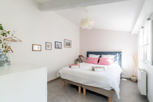 a white bedroom with a bed with pink pillows at Bois Flottés - Maisonnette 700m mer in Pornic