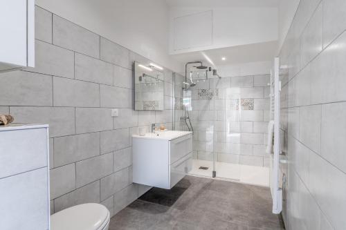 a white bathroom with a toilet and a sink at Bois Flottés - Maisonnette 700m mer in Pornic