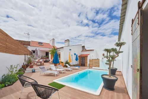 a backyard with a swimming pool and chairs and a house at Casa Bica D'Alva in Vila Alva
