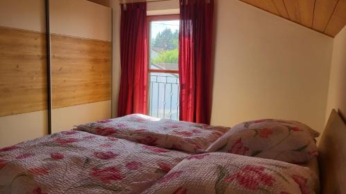 a bedroom with a bed and a window with red curtains at Ferienwohnung Strobl in Dießen am Ammersee
