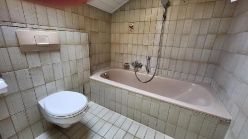 a bathroom with a tub and a toilet and a sink at Ferienwohnung Strobl in Dießen am Ammersee